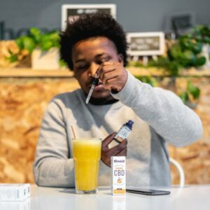 A young man squeezes a dropper into a glass of orange juice.