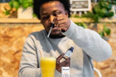 A young man squeezes a dropper into a glass of orange juice.
