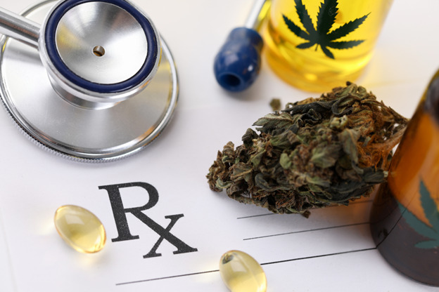 A stethoscope is placed on a prescription pad with the "Rx" symbol, suggesting a medical context. Surrounding the pad are cannabis buds and a bottle with a cannabis leaf symbol, containing oil. Additionally, there are yellow capsules, likely supplements or medications